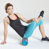 Athletic woman sitting on the Homedics Gladiator Vibration Foam Roller