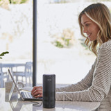 Black | Woman smiling while typing on tablet next to the Homedics TotalClean 4-IN-1 UV Portable Air Purifier in black