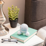 Blue | Blue Homedics Marbelous Mini Massager sitting on a table with lamp, plants, book, and eyeglasses