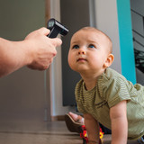 Black | Person takes forehead temperature reading from baby using the black Homedics Infrared Ear and Forehead Thermometer in black