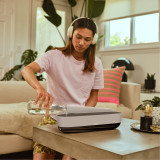 Khaki | A woman listens to music and adds more water to the Homedics® Fireside Ultrasonic Humidifier with Sound